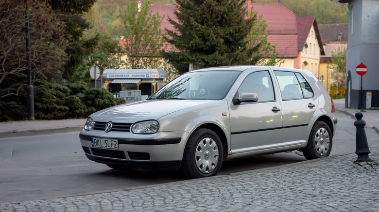 A silver Volkswagen Golf Mk4 parked on the street, front 3/4 view