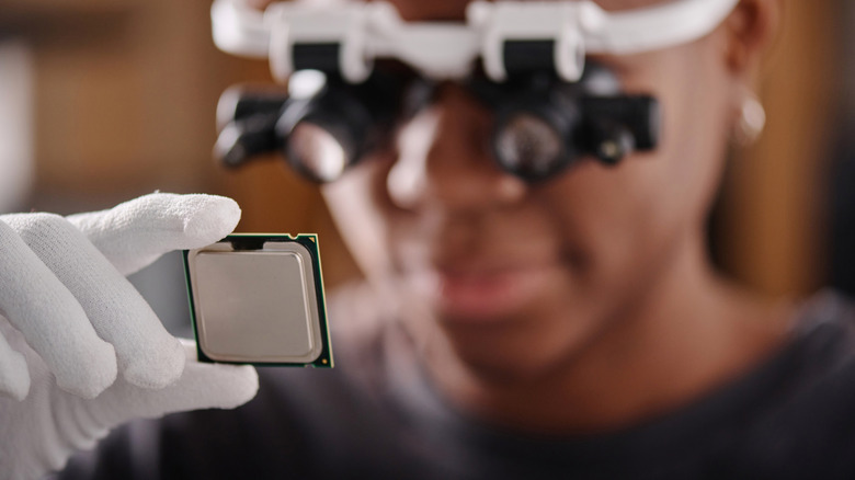 Person wearing magnifying goggles to examine CPU