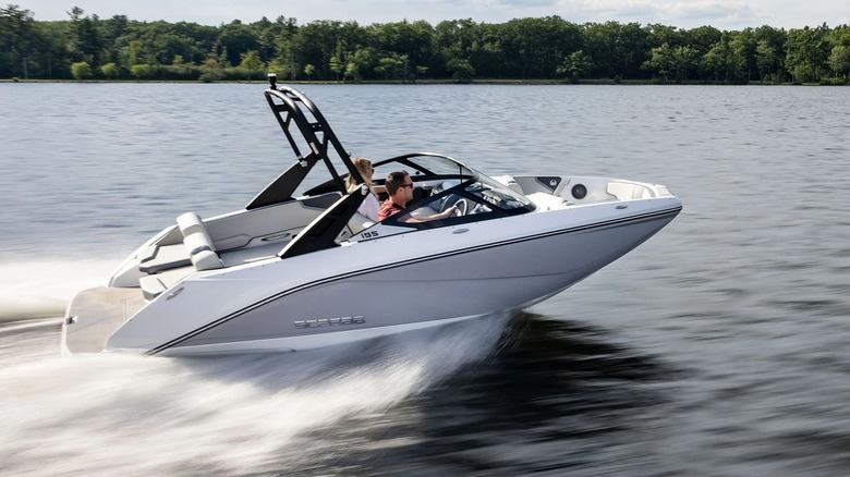 Scarab 195 SE racing across a lake with a forest in the background