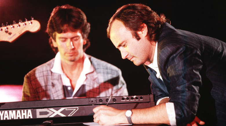 Progressive rock band Genesis, Tony Banks and Phil Collins on stage, Rome, Italy, 1985. Banks has a Yamaha DX7 keyboard.