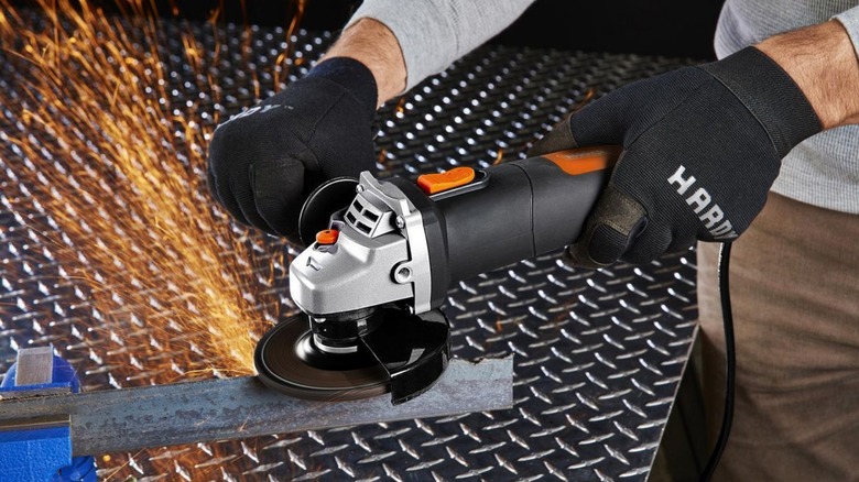 A person using a Warrior angle grinder with sparks shooting from it