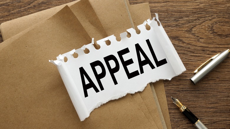 The word "Appeal" written in all caps on torn paper against a wooden background.