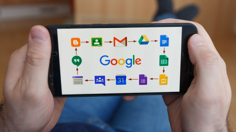 Man holding smartphone with icons of different Google products