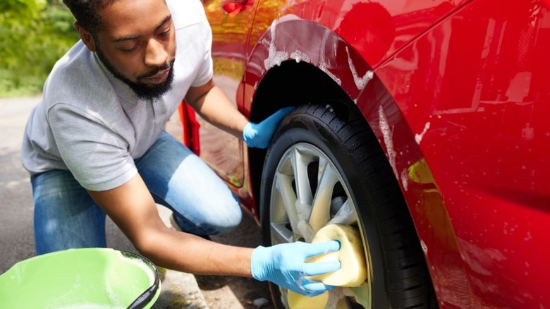 A person washing a red car