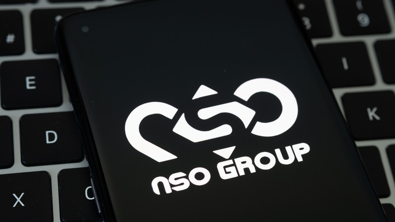 NSO Group logo on phone over MacBook