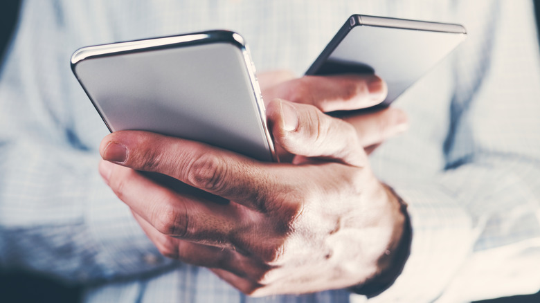 man holding two smartphones