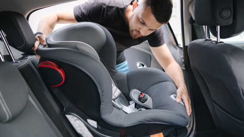 A father installs a front facing child car seat in his vehicle