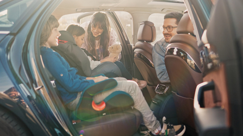 Parents ensure that their kids in the backseat are strapped into their car seat